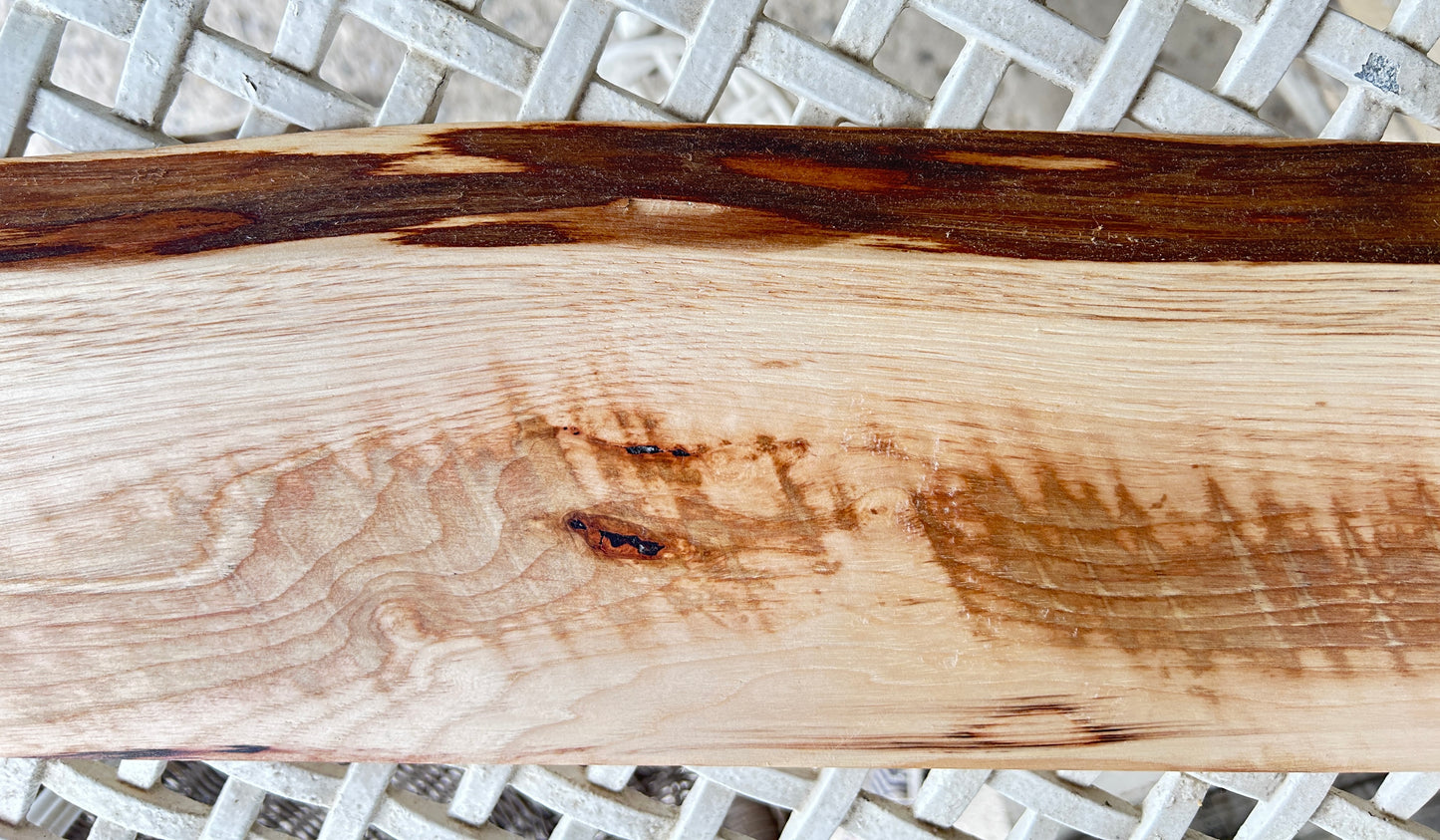 Close-up of a wooden board with visible grain and dark brown spots