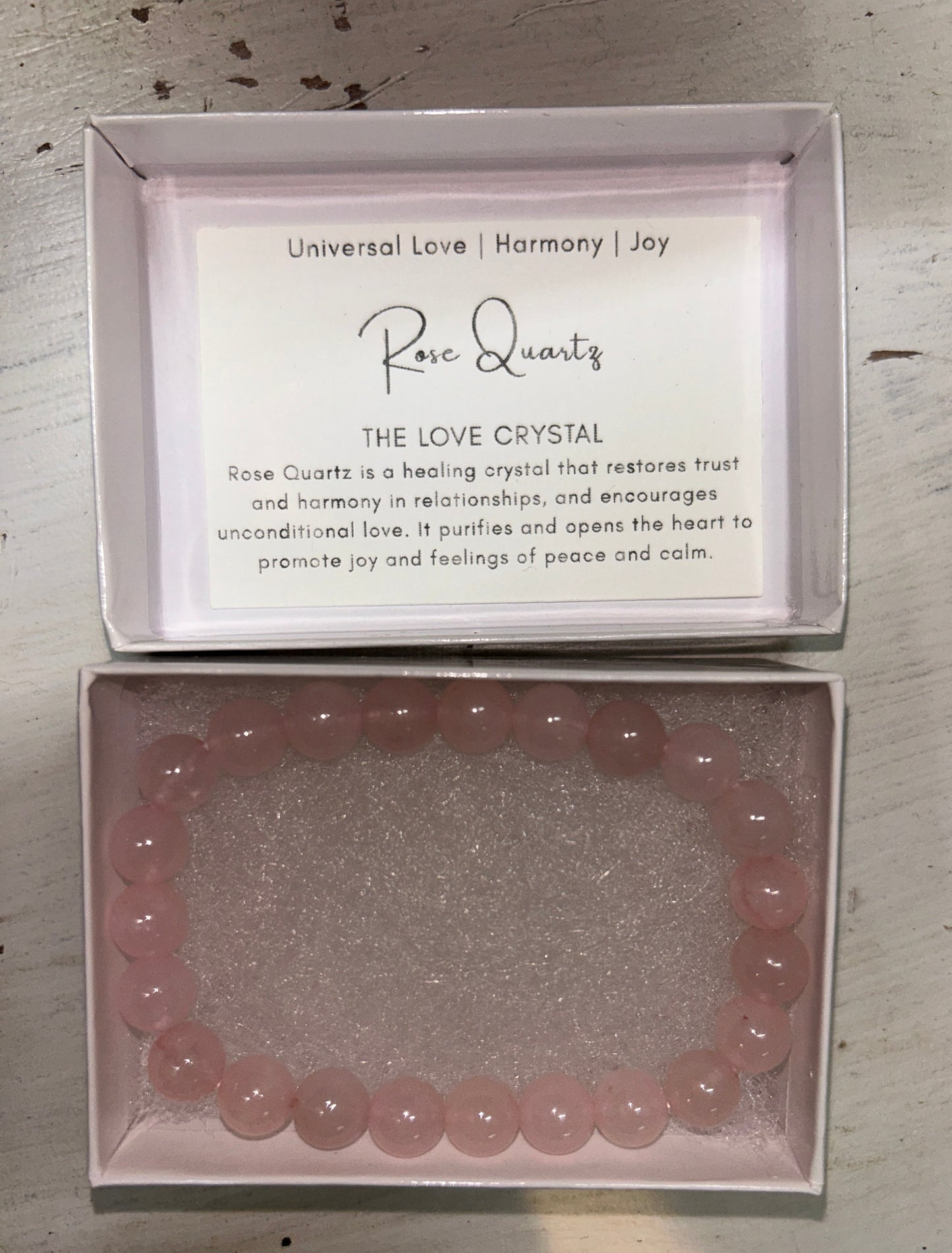 Rose quartz crystal bracelet in a box with a card on a wooden surface