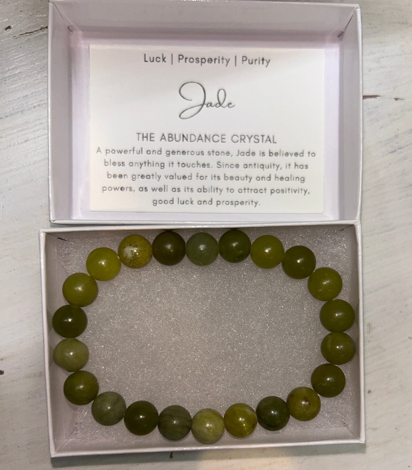 Green beaded bracelet in a box with a card on a wooden surface