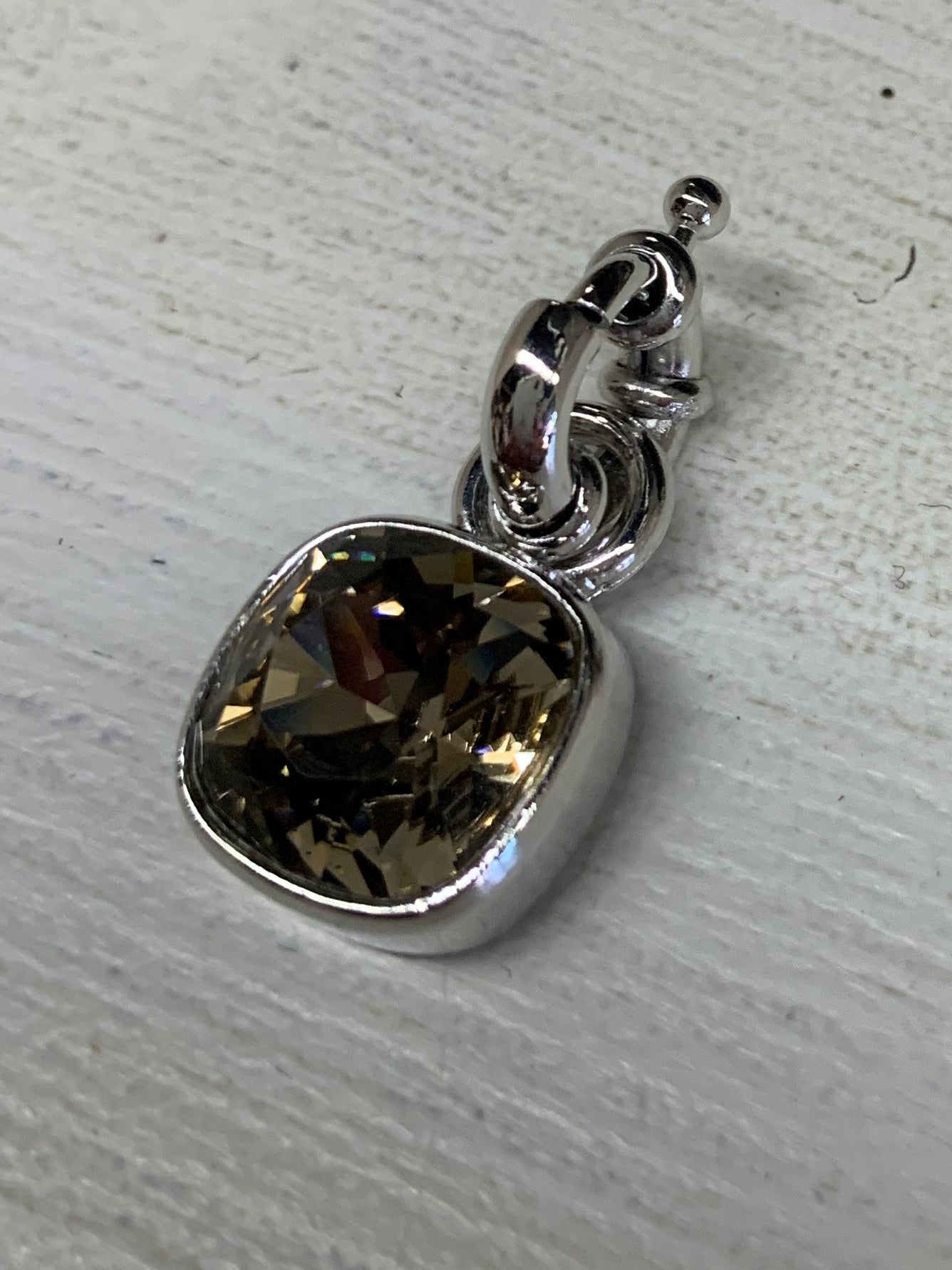 Silver pendant with a smoked topaz gemstone on a light gray surface