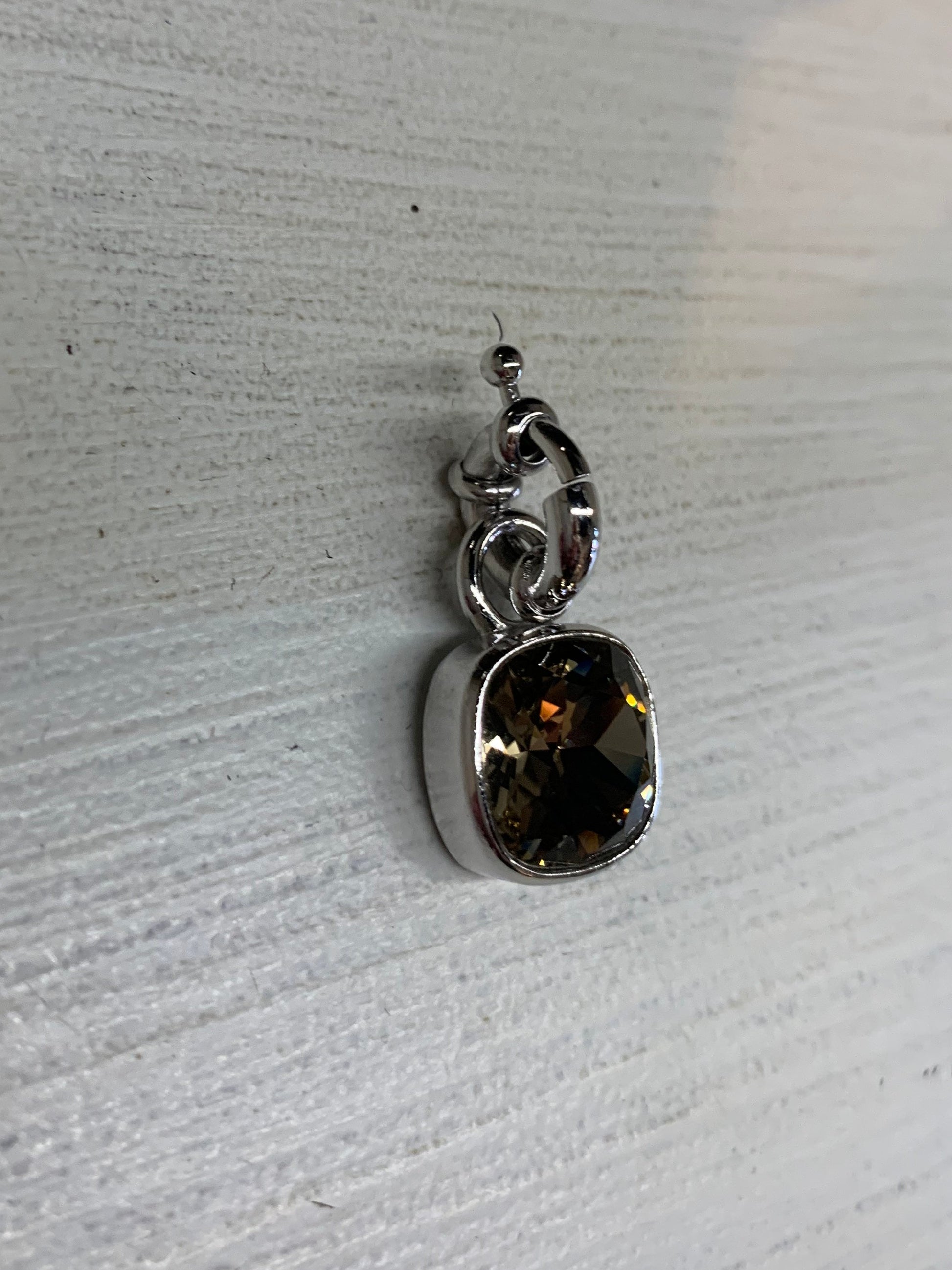 Silver pendant with a topaz gemstone on a light wooden surface