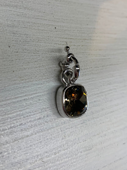 Silver pendant with a topaz gemstone on a light wooden surface