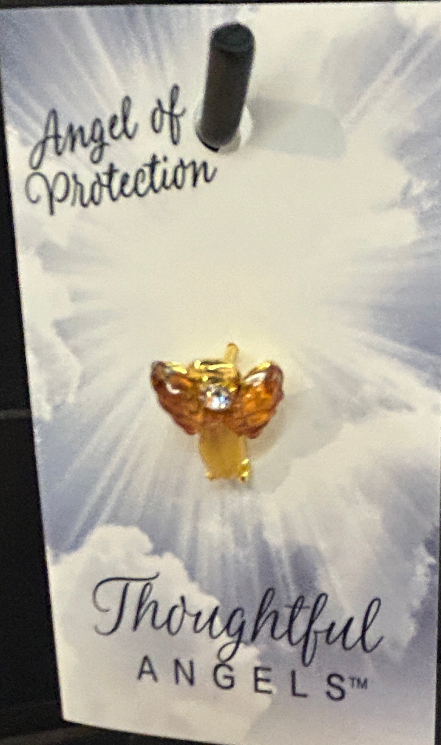 Earring packaging with 'Angel of Protection' design on a black surface