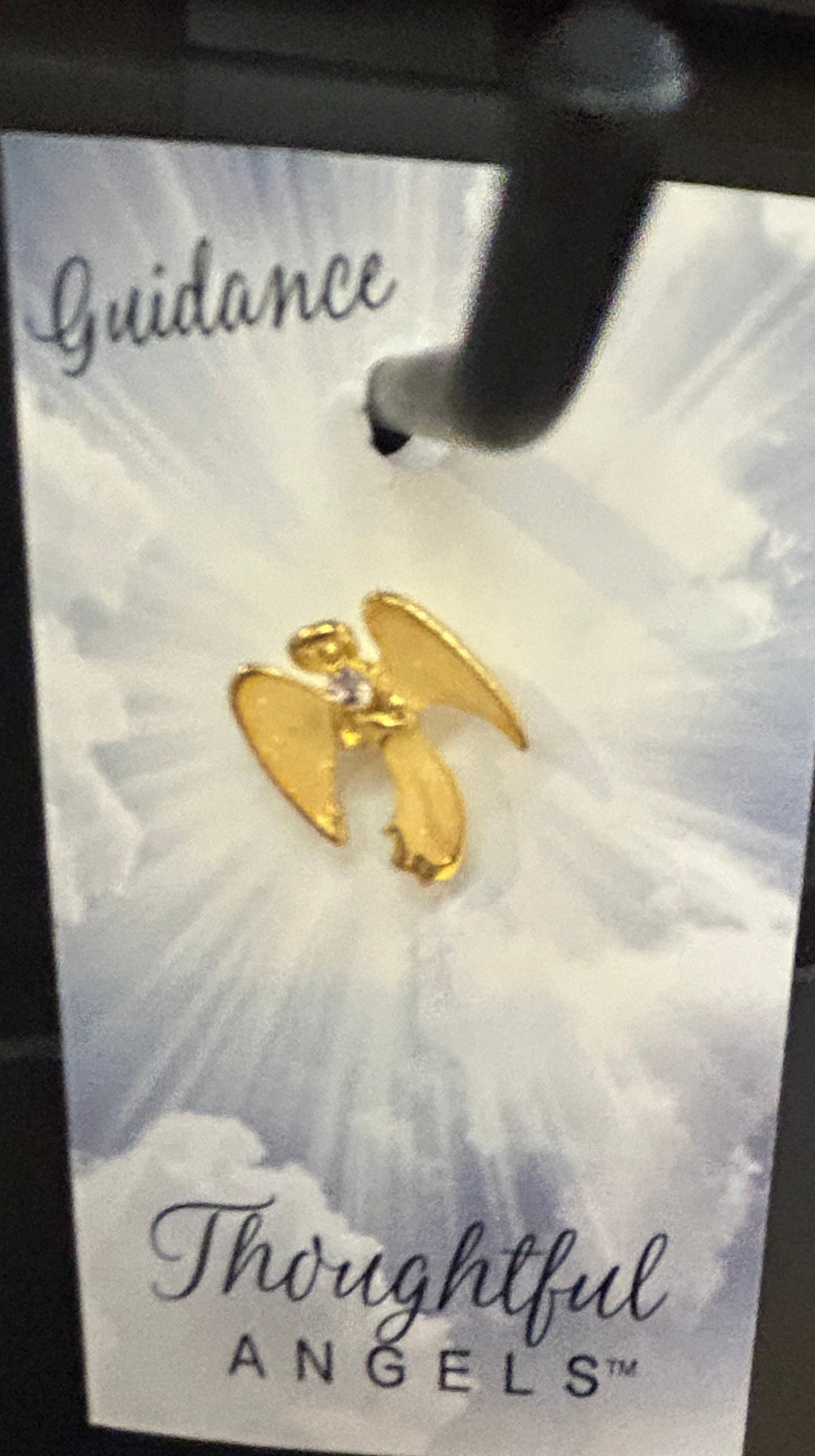 Gold angel earrings on a card with text in a display stand.